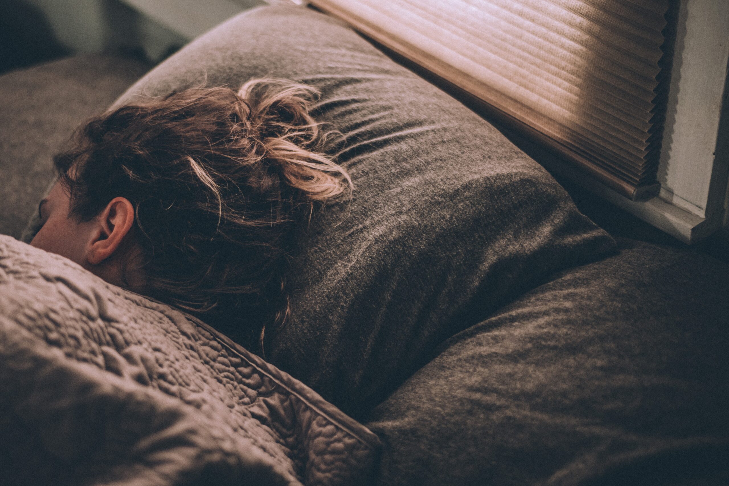 close up of the back of a womans head sleeping in a bed