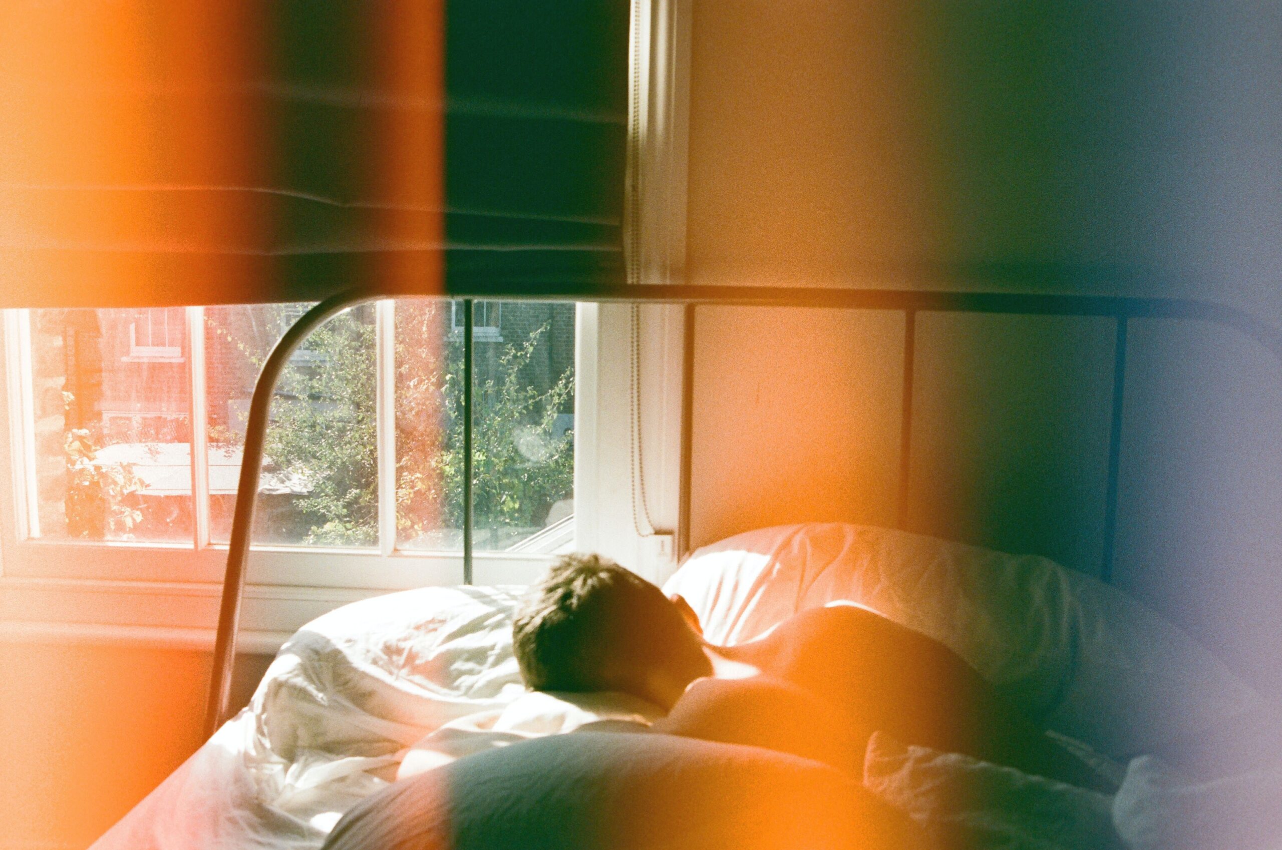 striped filter image of a person lying on a bed in front of a window