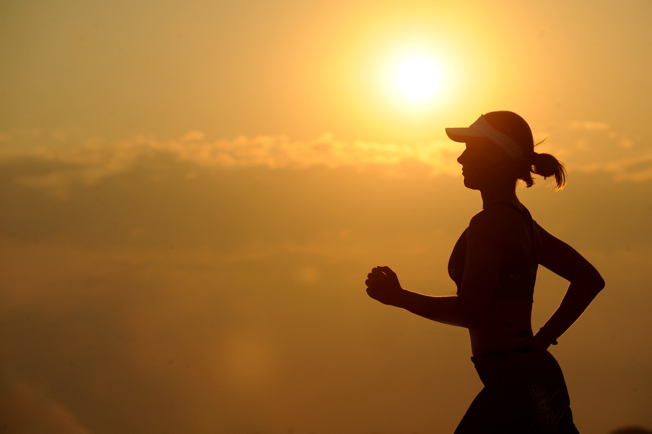 a woman runnnig against the silhouette of a sunset