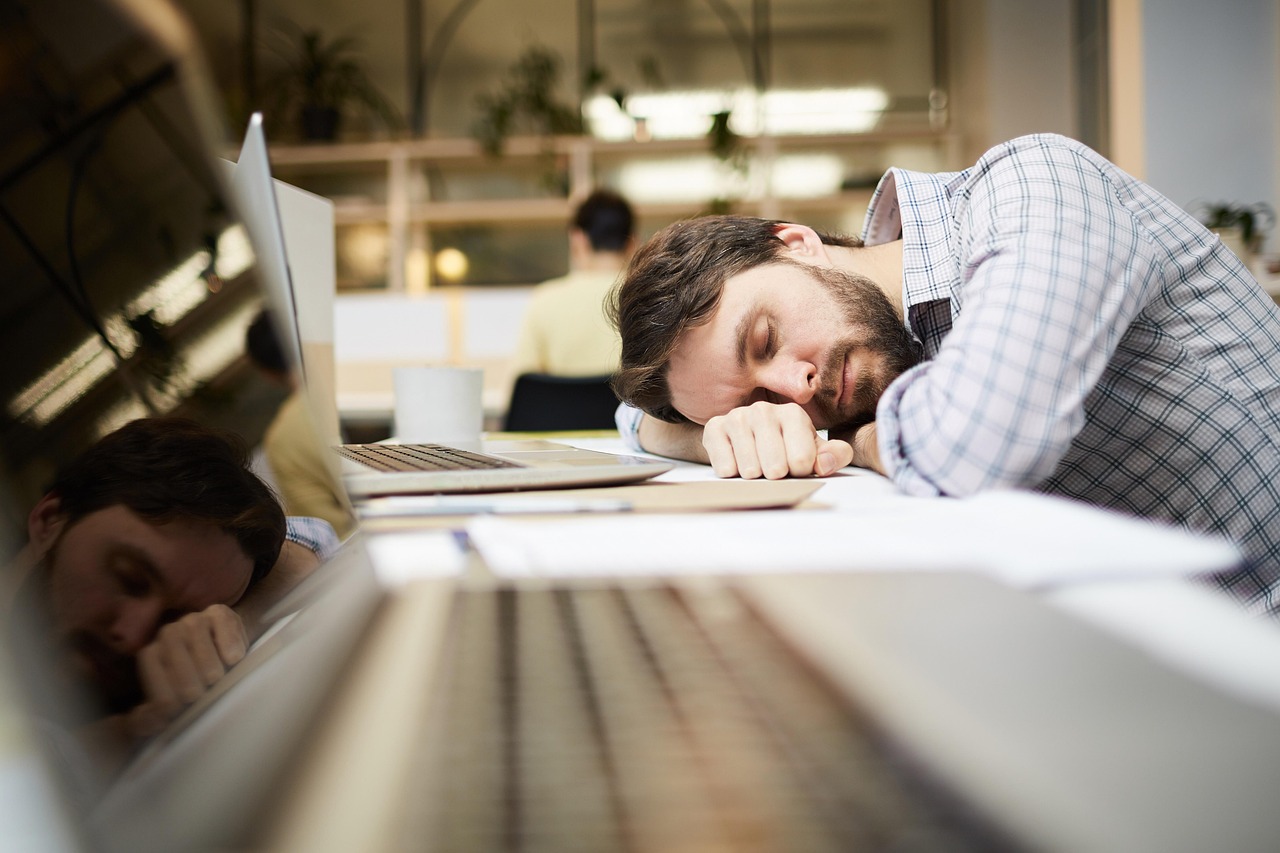 a man lying on his arms on a desk asleep