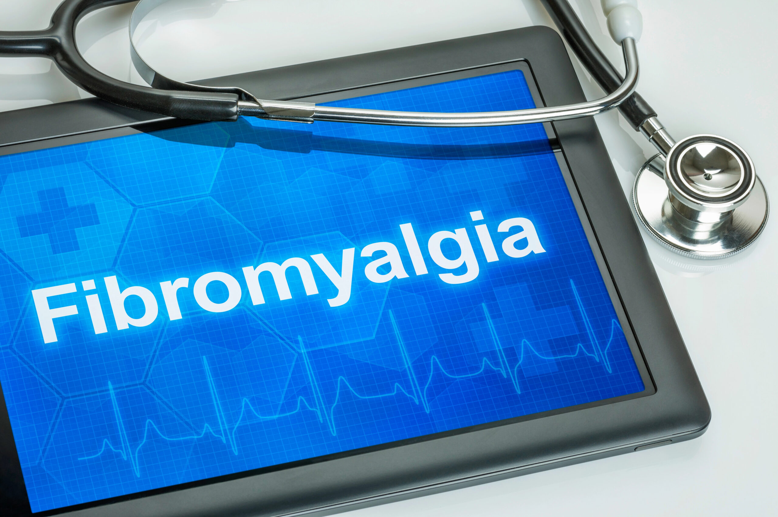 Digital tablet displaying the word Fibromyalgia with stethoscope and medical background